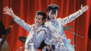 Two Japanese singers dressed in silver jumpsuits standing on stage