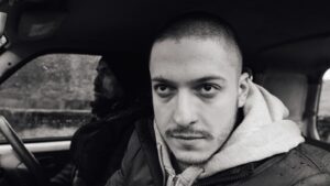 Two young men sitting in a car in black and white