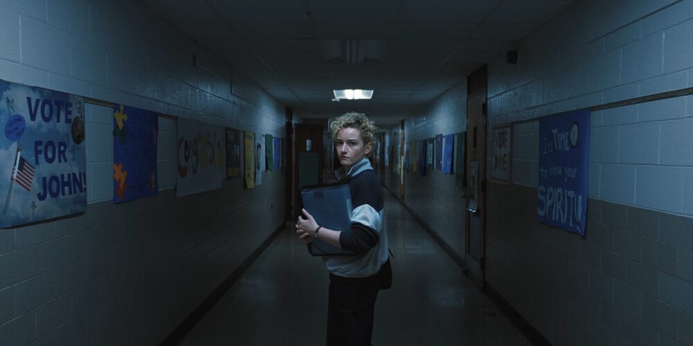 A young female teacher stood alone in a dark school hallway.