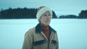 Emma Thompson standing alone in a snow-covered field wearing winter clothing.