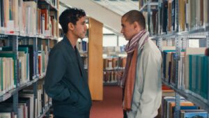 Two young Syrian men standing face-to-face in a deserted library.
