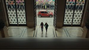 Two women walk in to a building, possibly a court, while police and a protest occur outside